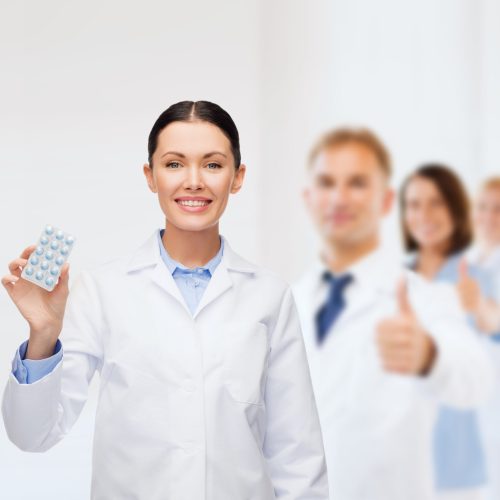 healthcare, medicine and pharmacy concept - smiling female doctor and with pills